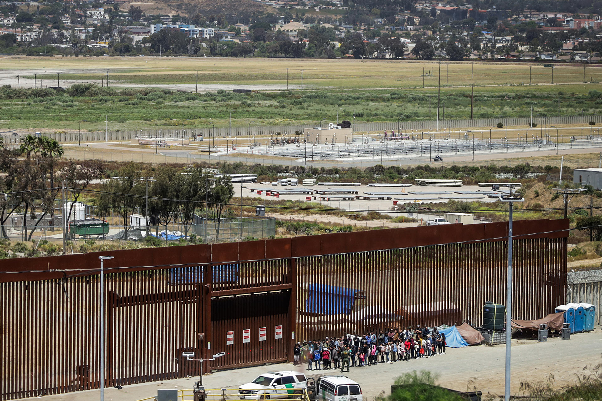 CAMINANTES. Migrantes permanecen en la línea divisoria entre México y EEUU, este martes en Tijuana (México). EFE
